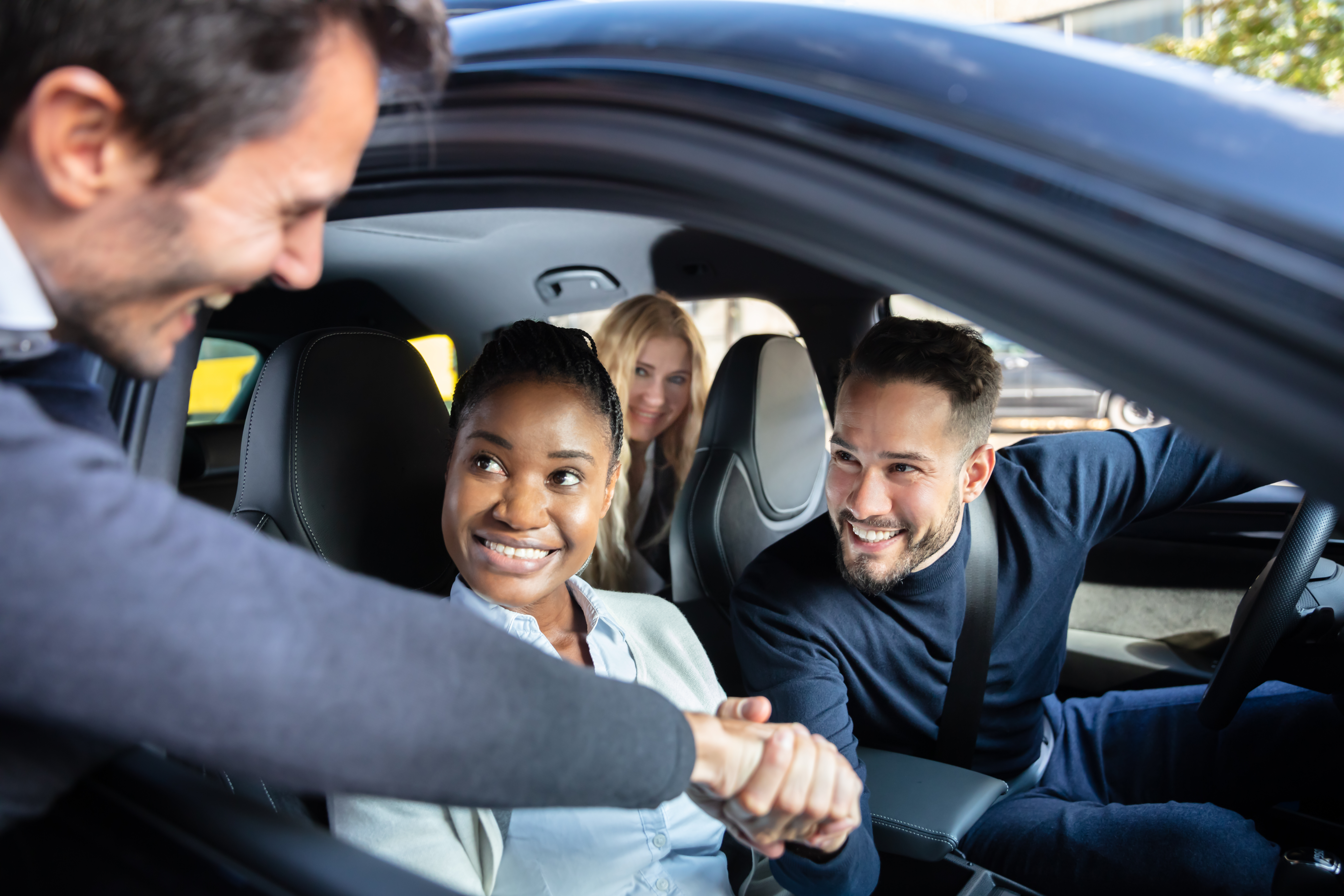 Man Shaking Hanks With Friends Sitting In Car Through Window