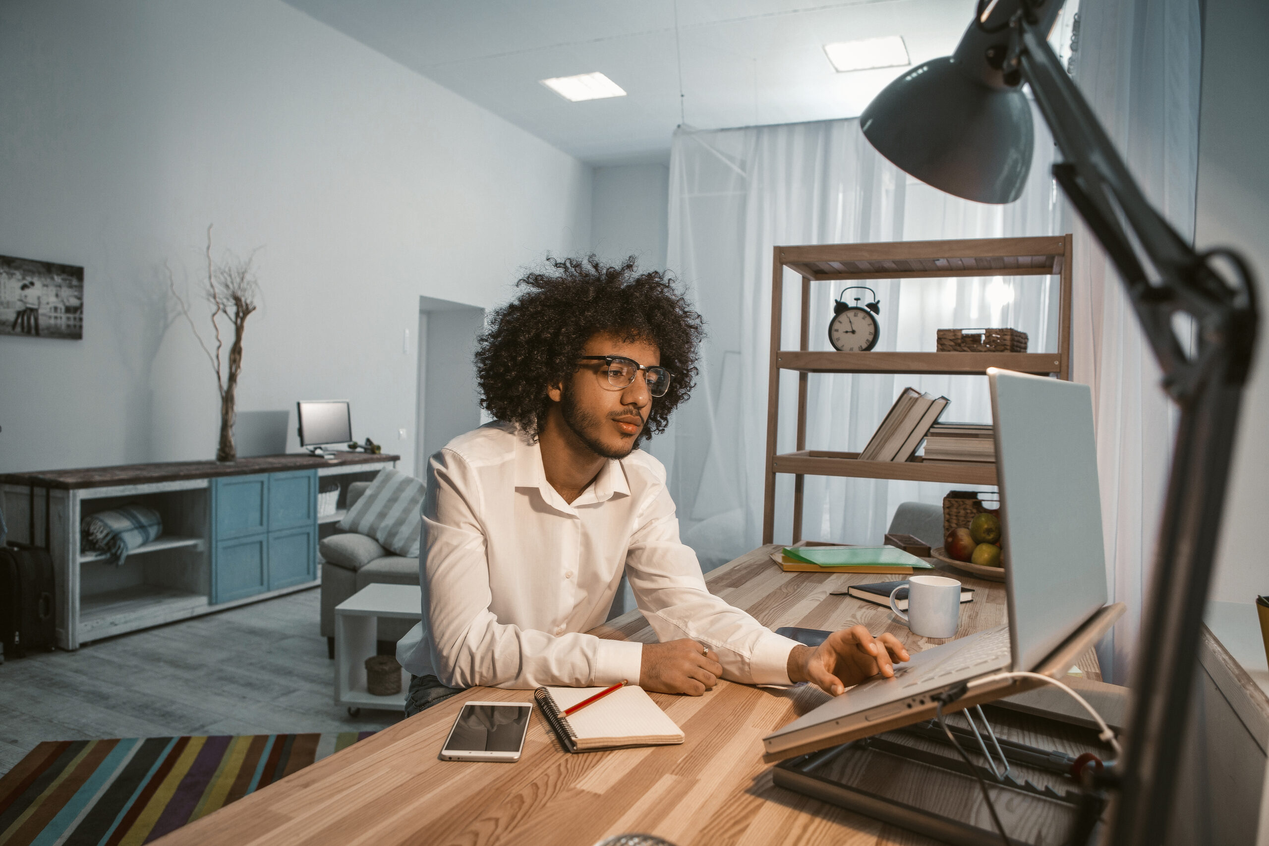 Creative man works laptop at home office interior.