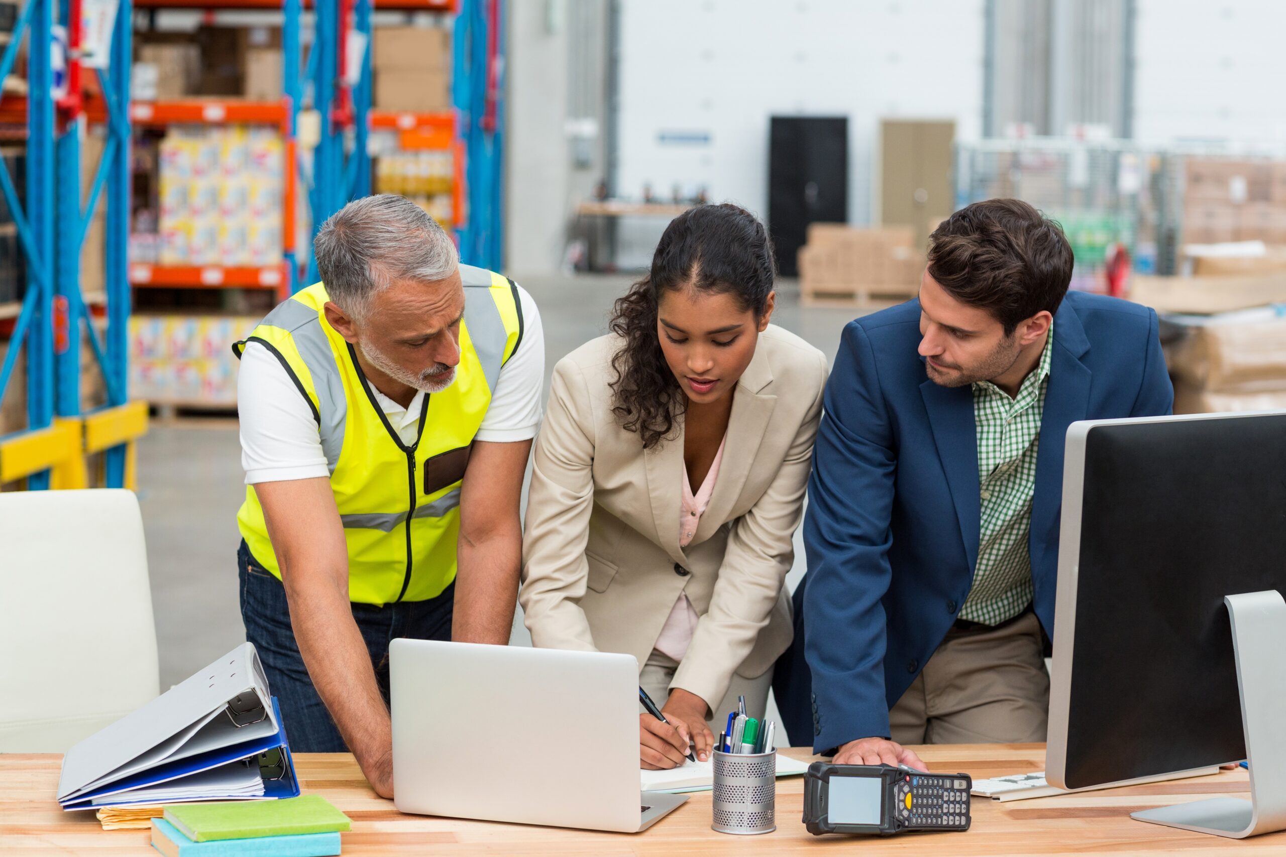 Warehouse managers and worker discussing with laptop